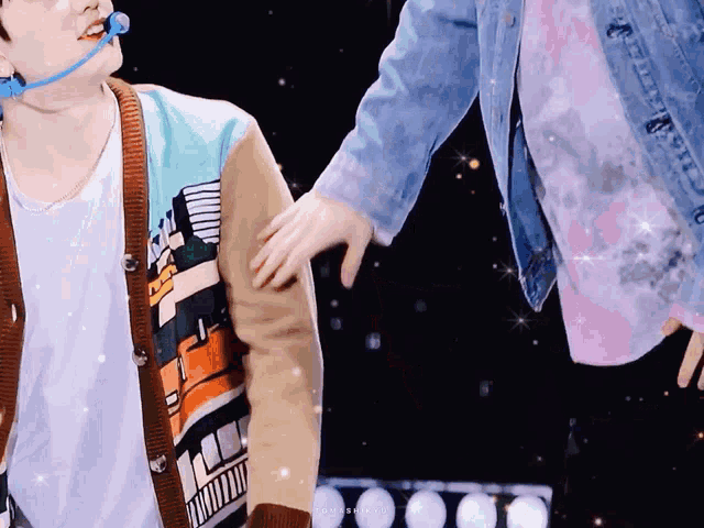 a man wearing a sweater with a city on it holds another man 's hand
