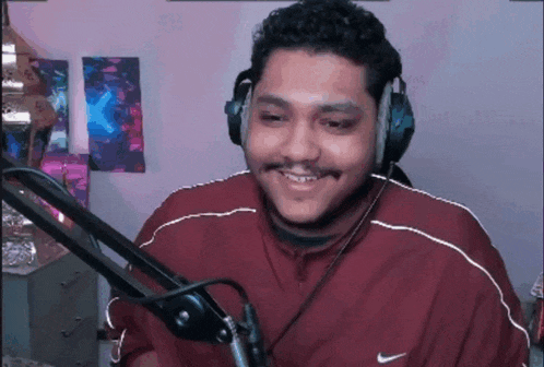 a man wearing headphones and a nike jacket is smiling