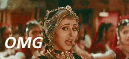 a woman with a lot of jewelry on her head is making a funny face while dancing in front of a crowd .