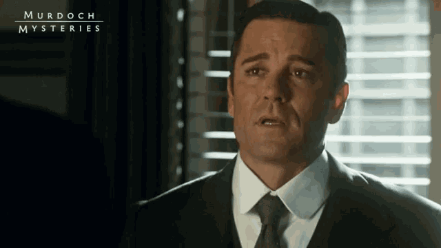 a man in a suit and tie is standing in front of a window with murdoch mysteries written on the bottom