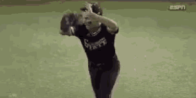 a baseball player in a black shirt is throwing a ball on a field .