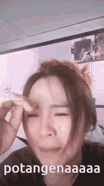 a woman is crying with her eyes closed while holding her head .