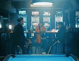 a pool table in a bar with people sitting at tables