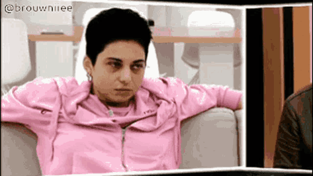 a woman in a pink jacket sitting on a couch
