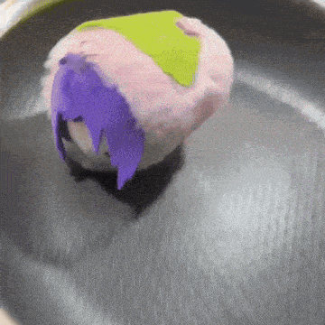 a stuffed animal with purple hair and a green leaf on top of it