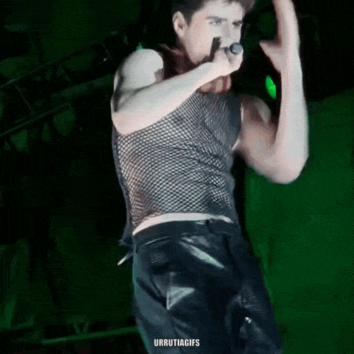 a man is singing into a microphone on a stage .