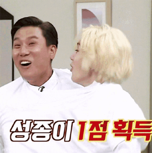 a man and a woman are hugging each other and the man is wearing a white shirt with korean writing on it .