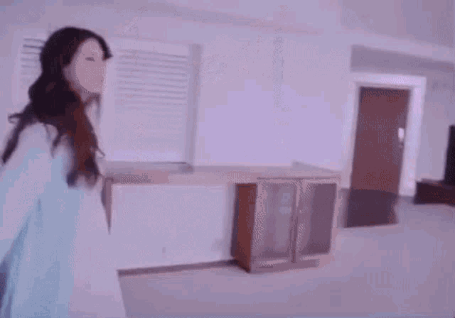 a woman in a blue dress is walking through an empty living room .