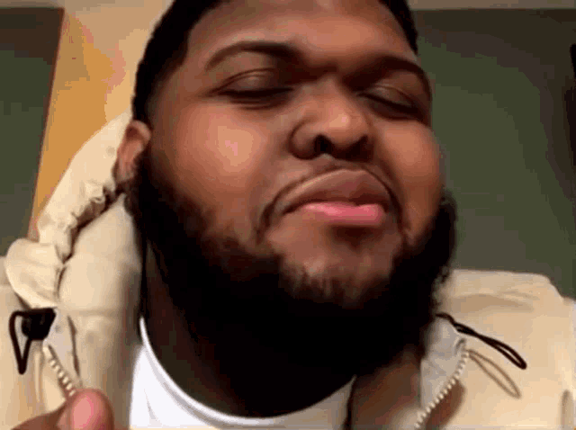a man with a beard is making a funny face with his eyes closed .
