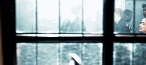 a man and a woman are looking out of a window .