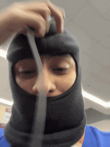 a person wearing a black balaclava is holding a piece of paper in front of their face