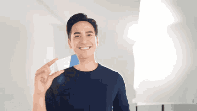 a man in a blue shirt is smiling and holding a card