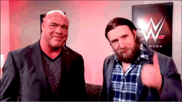 two men are standing next to each other and one is giving a thumbs up sign