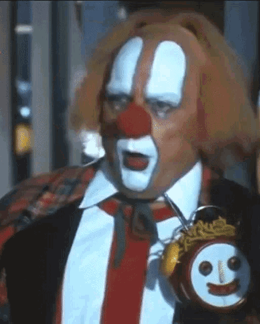 a clown in a suit and tie is holding a clock with a smiley face on it