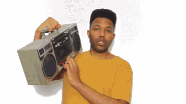a man wearing a yellow shirt is holding a boombox over his shoulder