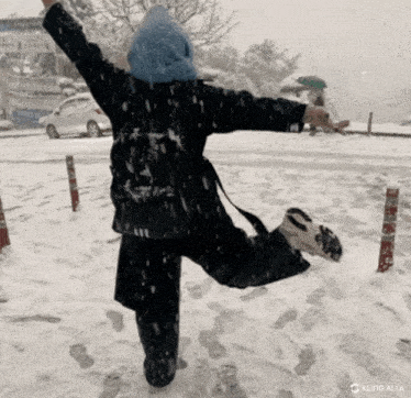 a person is standing in the snow with their arms outstretched in the air