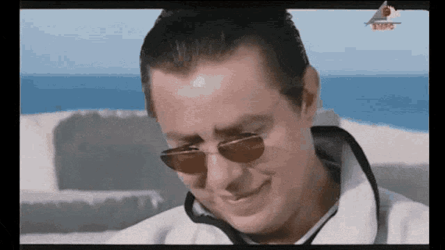 a man wearing sunglasses is smiling in front of a tv screen that says nfc