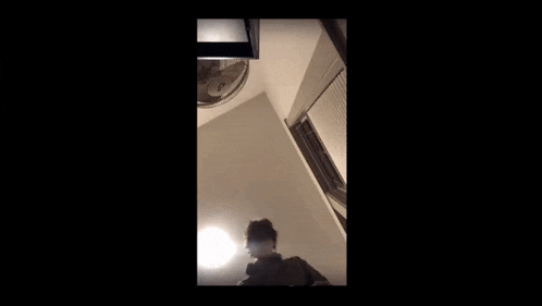 a person is standing in a room with a fan on the ceiling and a fan on the wall .