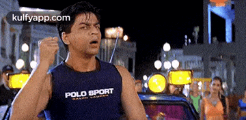 a man wearing a polo sport tank top is raising his fist in the air .