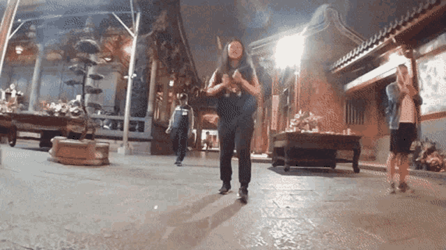 a woman wearing a mask is dancing in front of a building