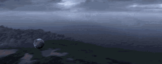 a globe is flying over a landscape with mountains in the distance