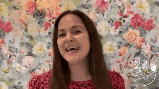 a woman is laughing in front of a floral wall with the words british podcast awards