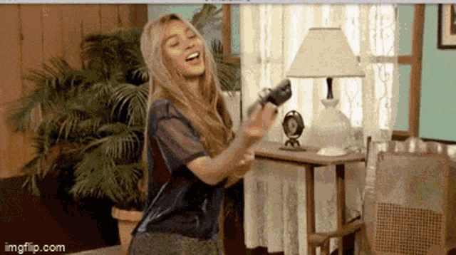 a woman is playing a video game in a living room while holding a remote control .