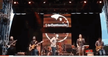 a group of men are playing instruments on a stage with a large screen behind them that says 1up