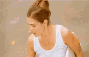 a woman in a white tank top is standing on a tennis court .
