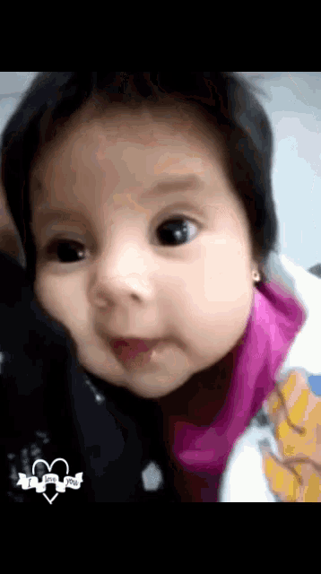 a close up of a baby 's face with a sticker that says i love you on it