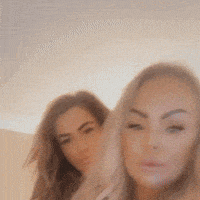 two women are standing next to each other and looking at the camera with their eyes closed