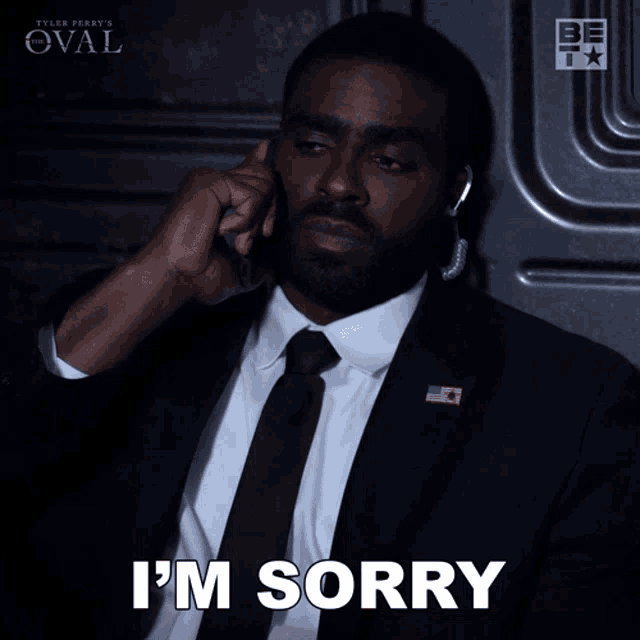 a man in a suit and tie says i 'm sorry while talking on a cell phone