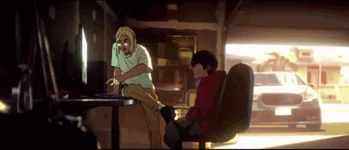 a couple of people are sitting in front of a computer .