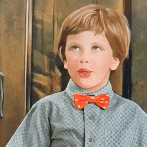 a young boy wearing a blue shirt and a red bow tie is making a funny face