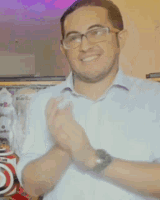 a man wearing glasses and a white shirt has a purple star behind him