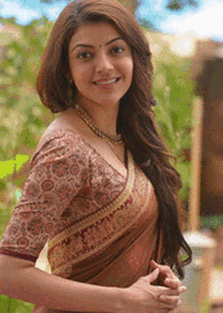 a woman wearing a blouse and a necklace is smiling