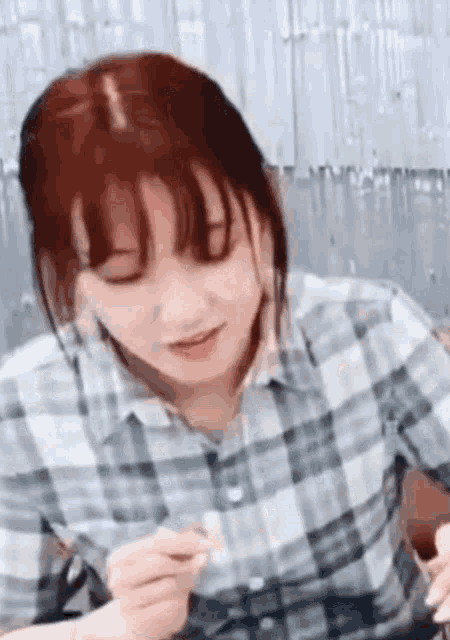 a woman in a plaid shirt is eating a sandwich with a fork .