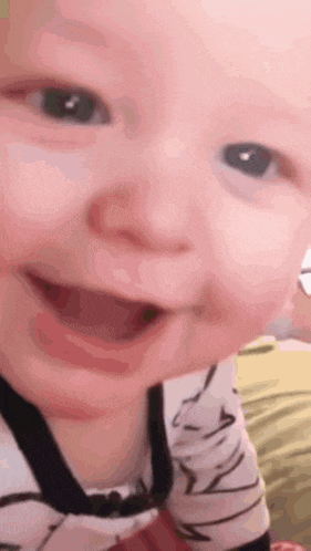 a baby is smiling and looking at the camera while wearing a striped shirt .
