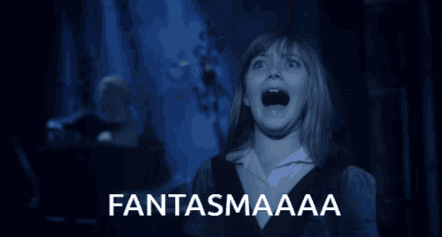 a girl is screaming in a dark room with the words fantasmaaaa behind her