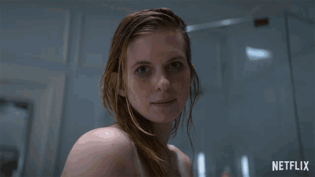 a woman with wet hair looks at the camera with a netflix logo behind her