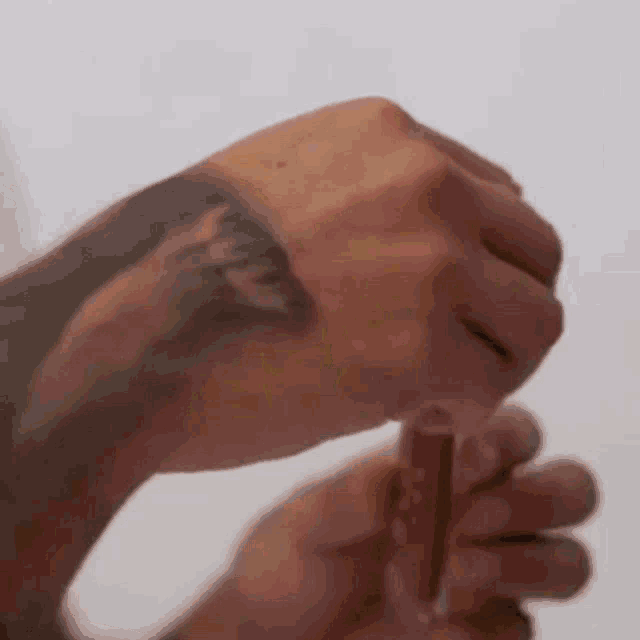 a close up of a person 's hand with a tattoo on it holding a piece of meat .