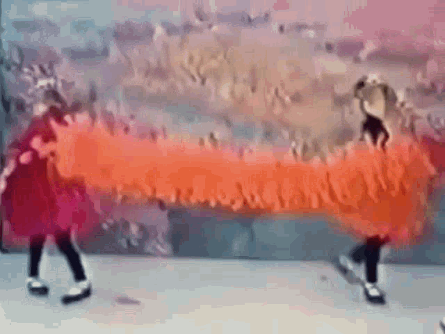 a couple of girls are standing next to each other in front of a large red painting .