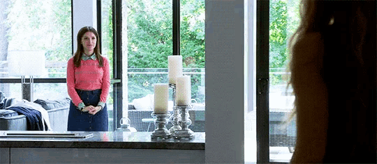 a woman in a pink shirt stands in front of a window