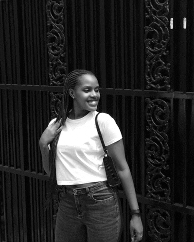 a black and white photo of a woman standing in front of a gate