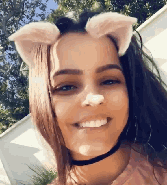 a woman wearing a choker and cat ears smiles for the camera