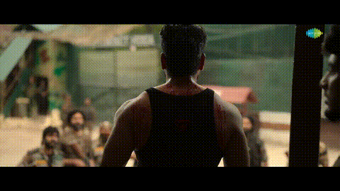 a man in a black tank top is standing in front of a crowd of people .