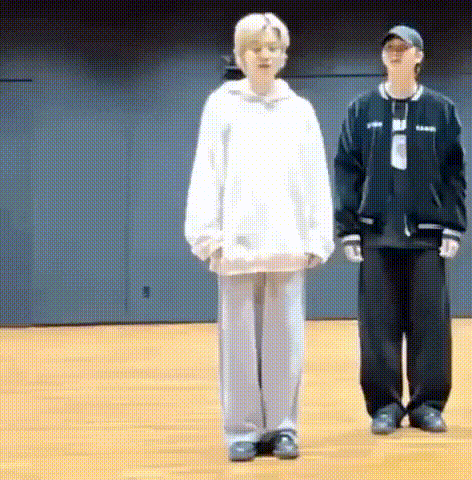 two people are standing next to each other on a wooden floor in a room .