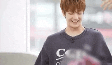 a young man wearing a sweater is smiling and looking down .