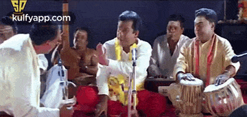 a group of men are sitting on the floor playing drums .