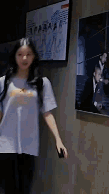 a woman in a blue shirt is standing in front of a wall with a picture of a man on it .